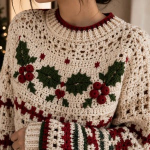 Peut inclure: Un pull en crochet de couleur crème orné d'un motif festif de houx et de baies. Le design présente des feuilles en crochet vert foncé et des grappes de baies rouge vif sur la poitrine, avec des rayures rouges et vertes aux poignets et à l'ourlet.
