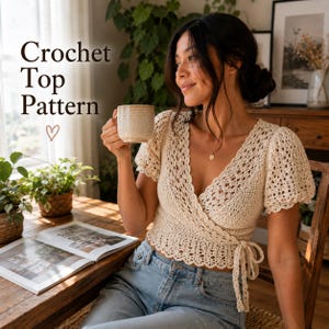 Könnte beinhalten: Ein cremefarbenes Wickeloberteil aus Häkelarbeit mit kurzen Puffärmeln, V-Ausschnitt und Bindegürtel in der Taille. Der Text "Crochet Top Pattern" und ein kleines Herzsymbol sind in der oberen linken Ecke des Bildes zu sehen.