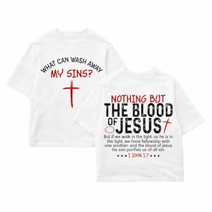 May include: White t-shirts with religious text and graphics. One shirt displays "WHAT CAN WASH AWAY MY SINS?" with a red cross. The other shirt has "NOTHING BUT THE BLOOD OF JESUS" with a cross and text from 1 John 1:7.