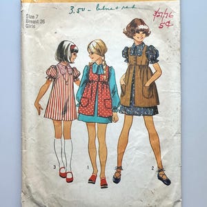 May include: Vintage Simplicity sewing pattern envelope. The envelope features illustrations of three girls in dresses. The text on the envelope includes "Simplicity", "Size 7", "Breast 26", and "Girls". The price is $1.00 in the USA and $1.10 in Canada.