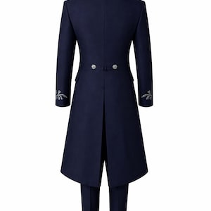 Op de afbeelding: Marineblauw formeel pak met een lange jas en bijpassende broek. De jas heeft zilveren geborduurde bloemendetails op de kraag en manchetten, en decoratieve knopen op de rug. Het pak is op maat gemaakt voor een slanke, elegante uitstraling.