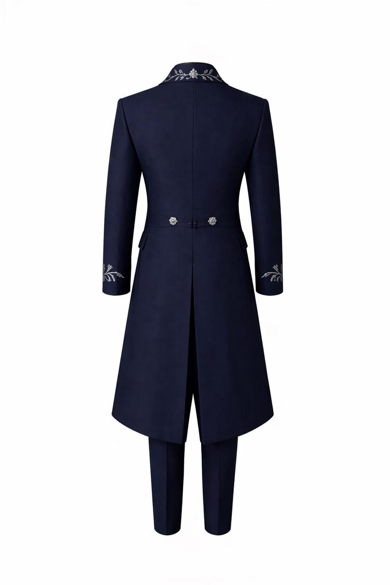 Op de afbeelding: Marineblauw formeel pak met een lange jas en bijpassende broek. De jas heeft zilveren geborduurde bloemendetails op de kraag en manchetten, en decoratieve knopen op de rug. Het pak is op maat gemaakt voor een slanke, elegante uitstraling.