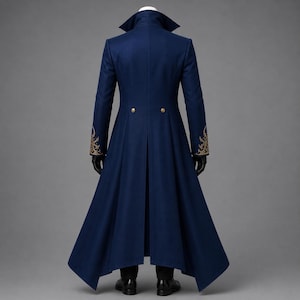 May include: A long, dark blue coat with a high collar and structured shoulders. The coat features gold-colored embroidery on the cuffs, two gold buttons at the waist, and a flared, floor-length hemline. The garment is displayed on a mannequin.