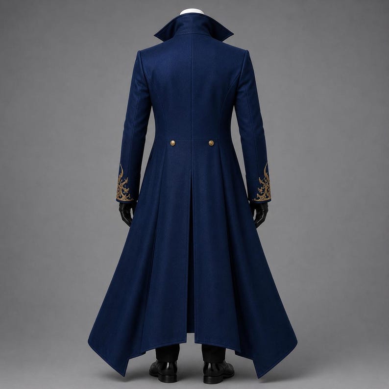 May include: A long, dark blue coat with a high collar and structured shoulders. The coat features gold-colored embroidery on the cuffs, two gold buttons at the waist, and a flared, floor-length hemline. The garment is displayed on a mannequin.