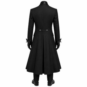 May include: A long black coat featuring a high collar, long sleeves with decorative cuffs, and a back vent. The coat includes a horizontal waist tab with two buttons. The ensemble is completed with black trousers and black leather gloves.