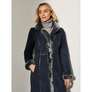 May include: A navy blue long coat with a gray shearling lining and trim. The coat features a button-down front, a notched collar, and cuffs with shearling trim. The coat is knee-length and has a tailored fit.