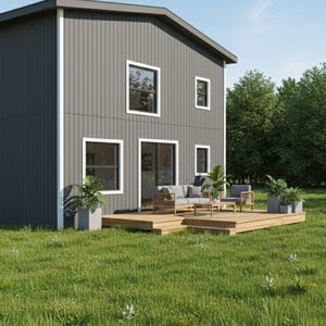 以下が含まれることがあります： ダークグレーのサイディングと白いトリムが施されたモダンな2階建ての家。家には複数の窓と、屋外用家具と鉢植えの植物が置かれた木製のデッキに通じる引き戸があります。家は緑の草と木々に囲まれています。