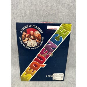 May include: A navy blue box for the board game Sequence. The box features the game's name in large, colorful letters. The box also has the text "A Game of Strategy" and "Minutes to Learn, A Lifetime to Master". The box shows a picture of people playing the game.