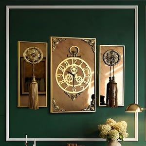 May include: Three framed wall art pieces with a vintage clock theme. The central piece is a large clock with gold gears and Roman numerals. The other two pieces feature decorative elements and tassels. The wall is painted a deep green.