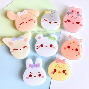 Pode incluir: Uma coleção de oito alfinetes de acrílico em cores pastel em forma de animais de desenho animado. Cada alfinete apresenta um design de animal diferente, incluindo um cão, um hamster, um coelho e um pintinho, com detalhes em forma de coração e laços. O texto "pastelslostar" é visível.