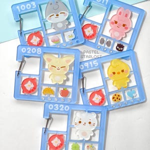 May include: A selection of light blue acrylic charms featuring cartoon animals like a bunny, fox, and bear. Each charm is divided into sections with small food-themed and floral accents. The text "PASTEL STARLOST" is visible on the charms.
