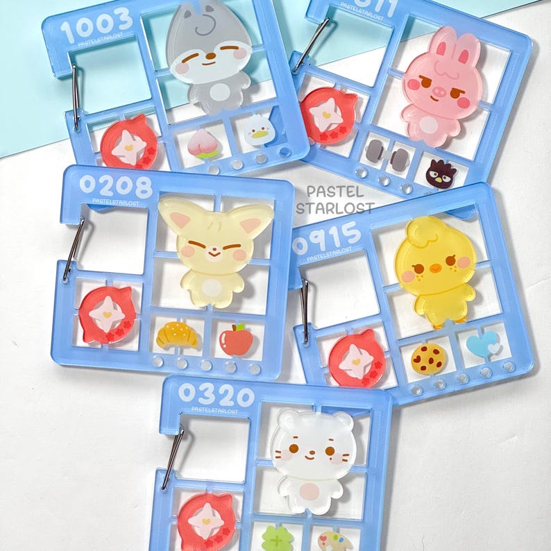 May include: A selection of light blue acrylic charms featuring cartoon animals like a bunny, fox, and bear. Each charm is divided into sections with small food-themed and floral accents. The text "PASTEL STARLOST" is visible on the charms.