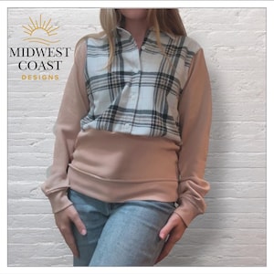 May include: A peach-colored sweatshirt with a white and black plaid shirt front. The shirt has long peach sleeves and a peach-colored bottom. The text "MIDWEST COAST DESIGNS" is in the upper left corner.