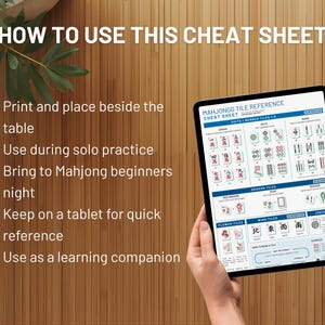 May include: A tablet displaying a Mahjong tile reference cheat sheet. The screen shows various tile types and game information. Text on the screen includes "MAHJONGG TILE REFERENCE CHEAT SHEET". The background is a wooden surface.