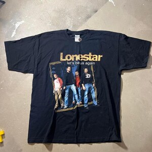 Könnte beinhalten: Schwarzes T-Shirt mit dem Namen der Band Lonestar in goldfarbenen Buchstaben. Darunter ist ein gerahmtes Bild der Bandmitglieder zu sehen. Der Text "let's be us again" ist unter dem Bandnamen auf dem T-Shirt aufgedruckt.
