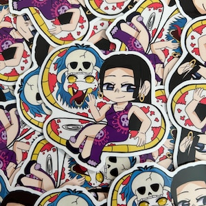 May include: A collection of anime-style stickers featuring a character in a purple dress with a skull design, seated on a yellow and red snake. The stickers have a white border and are scattered across the image.