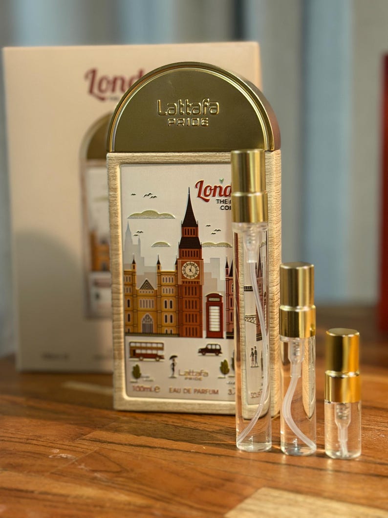 Pu&ograve; includere: Un set di profumi con tre flaconi spray trasparenti con tappi dorati, insieme a una scatola decorativa. La scatola mostra un'illustrazione a tema Londra con il Big Ben e un autobus rosso. Il marchio "Lattafa Pride" &egrave; visibile.