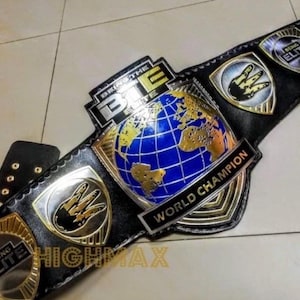 May include: Black leather wrestling championship belt with gold and silver accents. The belt features a blue and gold globe design, the text "WORLD CHAMPION", and the words "BRING THE ELITE".