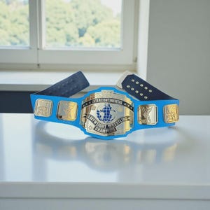 May include: A blue and gold Intercontinental Heavyweight Wrestling Championship belt. The belt features a central gold plate with a globe design and the words "Intercontinental Heavyweight Wrestling Champion". The belt has blue straps and gold side plates with the letters "WF".
