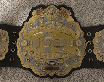 May include: A gold and silver heavyweight championship belt with the text "IWR CHAMPION" and "HEAVYWEIGHT" on the front. The belt has a black leather strap and two side plates with engraved names.