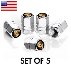 May include: Set of five silver-colored tire valve stem caps. Each cap features the Porsche logo in black, red, and gold. The caps are hexagonal in shape and have a threaded interior. The text "SET OF 5" is displayed in black.