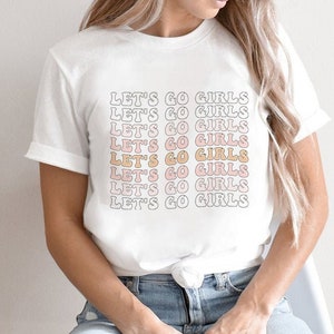May include: A white t-shirt with the text "Let's Go Girls" repeated in a gradient of pink, orange, and yellow.