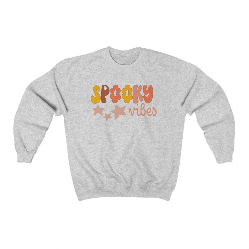 May include: A gray sweatshirt with the text "SPOOKY vibes" in orange, yellow, and pink letters. There are three pink stars above the text.