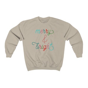 May include: A light beige sweatshirt with the text "merry & bright" in colourful script.