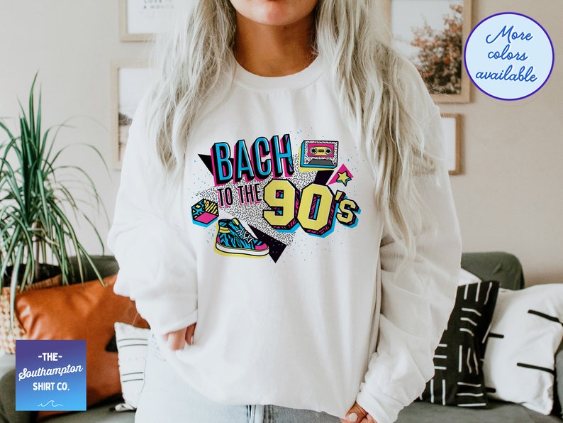 May include: White sweatshirt with a graphic print that says "Back to the 90's" in colorful, retro-style lettering. The graphic also includes a cassette tape, a star, and a sneaker.