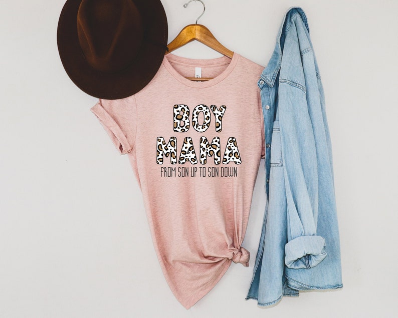 May include: A pink t-shirt with a leopard print design that says "Boy Mama" and "From Son Up To Son Down" in black text.