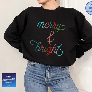 May include: Black sweatshirt with the text "merry & bright" in colourful script.