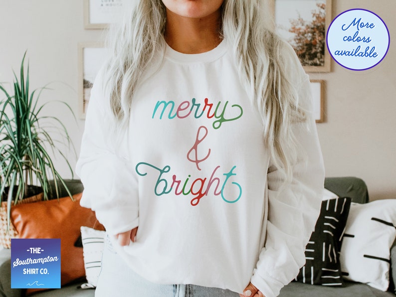May include: White sweatshirt with the text "merry & bright" in colourful cursive lettering.