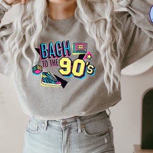 May include: A gray sweatshirt with a graphic print that says "Back to the 90's" in colorful, retro-style lettering. The graphic also includes a cassette tape, a star, and a sneaker.