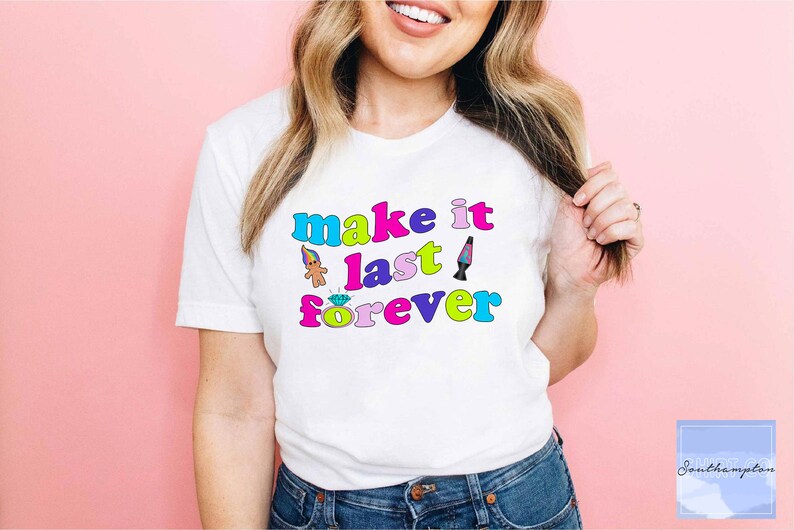 May include: White t-shirt with the text "make it last forever" in colorful retro font. The text is surrounded by small 90s-themed graphics, including a troll doll, a diamond ring, and a lava lamp.