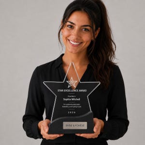 Puede incluir: Un premio en forma de estrella transparente con el texto "STAR EXCELLENCE AWARD" y "SHINE & ACHIEVE". El premio lo sostiene una persona que lleva una camisa negra. El premio tiene una base negra e incluye el nombre "Sophia Mitchell".
