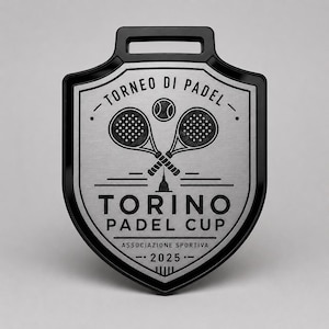 Può includere: Una medaglia a forma di scudo con bordo nero e centro argentato. Presenta un grafico con due racchette da padel incrociate e una pallina, con il testo TORNEO DI PADEL, TORINO PADEL CUP, ASSOCIAZIONE SPORTIVA e 2025 inciso in nero.