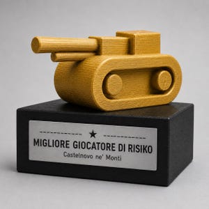 Può includere: Una statuetta a forma di carro armato color oro con superficie testurizzata poggia su una base rettangolare nera. Una targhetta in metallo argentato sul davanti presenta un'icona a stella e il testo "MIGLIORE GIOCATORE DI RISIKO" e "Castelnovo ne' Monti".