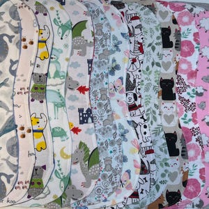 May include: A collection of cloth pads with various patterns, including whales, bears, cats, and floral designs. The pads are in a variety of colors, including blue, pink, and green. The pads are designed for feminine hygiene.