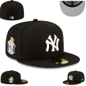 May include: Black baseball cap featuring the New York Yankees logo in white on the front. The cap has a flat brim and a structured fit. A patch with a crest design is on the side. The MLB logo is on the back.