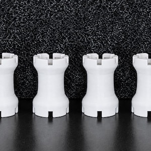 May include: Six identical white chess rook pieces arranged in a horizontal row. Each rook features a cylindrical body with a flared base and a crenellated top, characterised by a series of rectangular notches cut into the upper rim of the piece.