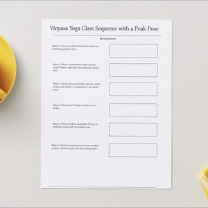 Könnte beinhalten: Ein weißes Blatt Papier mit dem Titel "Vinyasa Yoga Class Sequence with a Peak Pose" und einer Reihe von Aufforderungen für einen Yogakurs. Eine gelbe Tasse und Untertasse befinden sich in der oberen linken Ecke. Eine gelbe Schale und ein Stift sind unten rechts.