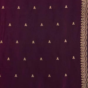 Peut inclure: Un textile bordeaux profond avec des broderies dor&eacute;es complexes. Le tissu pr&eacute;sente un motif r&eacute;p&eacute;t&eacute; de petits motifs floraux dor&eacute;s orn&eacute;s. Une bordure dor&eacute;e d&eacute;taill&eacute;e longe le bord, ajoutant une touche d'&eacute;l&eacute;gance. Le design sugg&egrave;re un v&ecirc;tement luxueux ou une pi&egrave;ce d&eacute;corative.