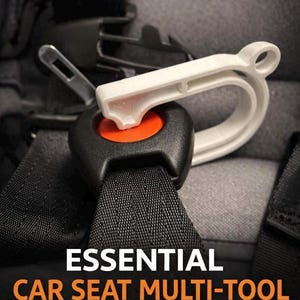 May include: A white car seat multi-tool is inserted into a black car seat buckle with an orange button. The tool is designed to assist with car seat installation. The text "ESSENTIAL CAR SEAT MULTI-TOOL" is displayed in white and orange.
