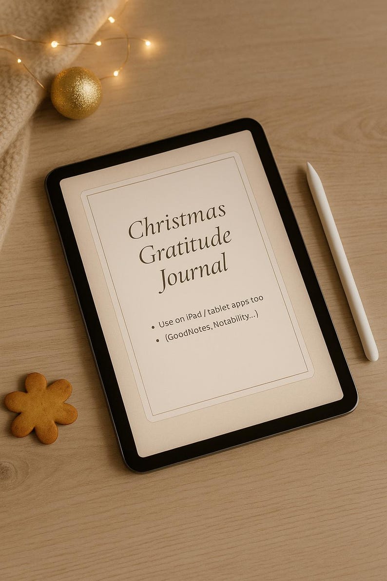 May include: A digital Christmas Gratitude Journal displayed on a tablet. The screen shows the title and instructions for use with iPad apps. A white stylus rests beside the tablet. A gold bauble and a gingerbread biscuit are also present.