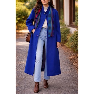 May include: A long, vibrant blue coat with a button closure, paired with light-wash jeans and brown boots. A colorful scarf adds a pop of color. A brown purse is worn over the shoulder. The coat is a classic outerwear piece.