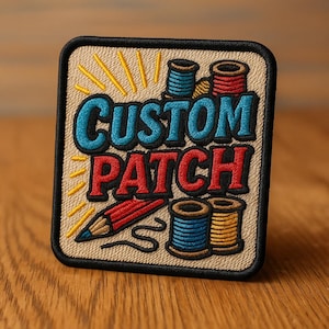 Può includere: Toppa ricamata con le parole "CUSTOM PATCH" in blu e rosso, con una matita e rocchetti di filo. La toppa ha uno sfondo beige con un bordo nero e raggi gialli.