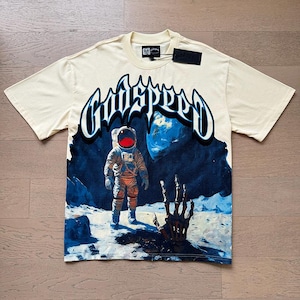 Könnte beinhalten: Cremefarbenes T-Shirt mit einer Grafik eines Astronauten auf dem Mond und dem Wort "GODSPEED" in einer stilisierten Schriftart. Der Astronaut trägt einen orangefarbenen und grauen Raumanzug. Ein schwarzes Etikett ist am Shirt befestigt.