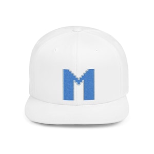 May include: A white baseball cap with a flat brim. The cap features a large, embroidered blue letter "M" on the front. The letter has a textured, denim-like appearance, adding a unique touch to the hat.