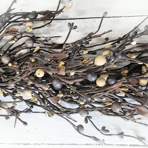 May include: A brown and beige berry garland with small brown branches and beige and grey berries.