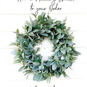 May include: A green, leafy wreath made of faux greenery. The wreath is hanging on a white wooden background. The text "Add a Matching Wreath to your Order" is above the wreath, and the text "Link in Listing" is below the wreath.